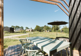 Zona pranzo all'aperto con ombrellone presso Barn, Nature house, Holiday park De Klepperstee, Paesi Bassi.