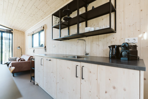 Moderne køkken i træhus med sorte åbne hylder og kaffemaskine i Barn, De Klepperstee, Holland.