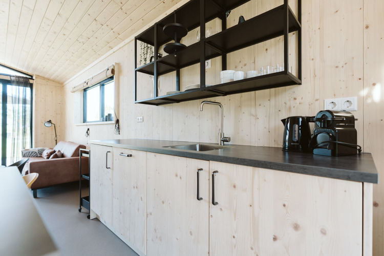 Moderne houten keuken met zwarte open planken en koffiemachine in Barn, De Klepperstee, Nederland.