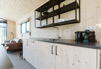 Moderne køkken i træhus med sorte åbne hylder og kaffemaskine i Barn, De Klepperstee, Holland.
