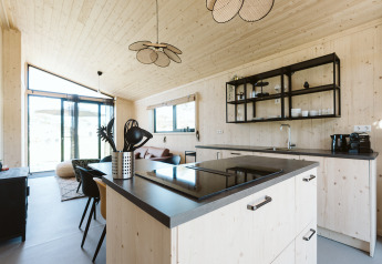 Moderne træbeklædt køkken og stue i naturhus i Holiday park De Klepperstee, Nederlandene, med store vinduer.