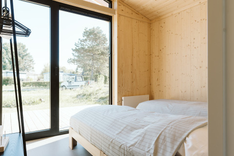 Helles Schlafzimmer mit Holzwänden und großen Fenstern im Barn Naturhaus im De Klepperstee, Niederlande.