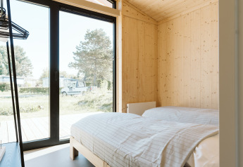 Lichte slaapkamer met houten wanden en grote ramen in Barn, een natuurhuisje op De Klepperstee, Nederland.
