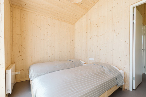 Chambre avec deux lits simples et murs en bois clair dans une maison nature au parc De Klepperstee, Pays-Bas.