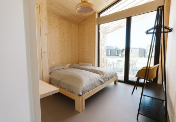 Moderne slaapkamer met houten wanden, twee bedden en grote ramen in Barn, De Klepperstee, Nederland.