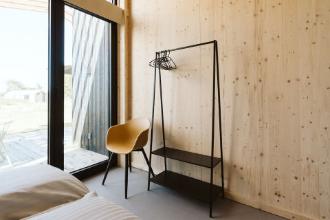 Moderne kamer met houten wanden, gele stoel en rek bij De Klepperstee, Nederland.