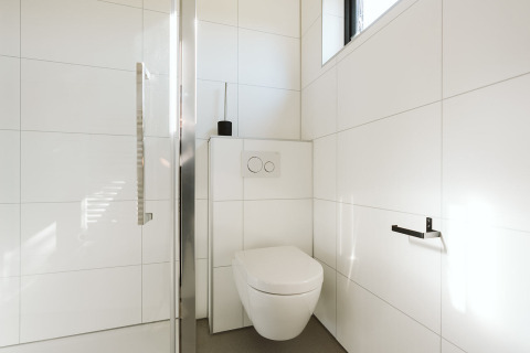 Moderne badkamer in Nature house Barn, De Klepperstee, Nederland, met hangtoilet en witte tegels.