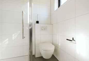 Moderne badeværelse på Nature house Barn, De Klepperstee, Holland, med væghængt toilet og hvide fliser.