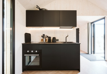 Cocina moderna negra en una tiny house del Holiday park De Klepperstee, Países Bajos, con interior luminoso.