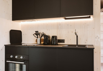 Moderne zwarte kitchenette met oven, gootsteen en keukengerei in tiny house Punt bij De Klepperstee, Nederland.