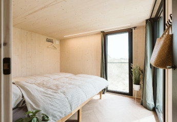 Lichte slaapkamer in Punt tiny house op vakantiepark De Klepperstee in Nederland met grote ramen.