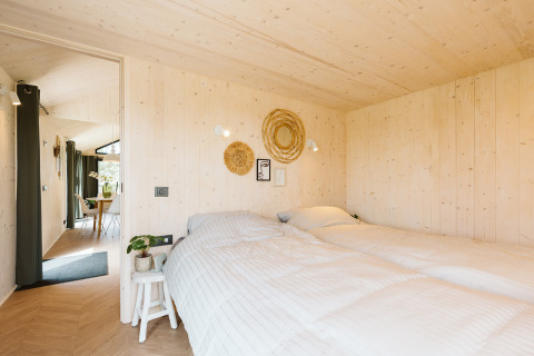 Dormitorio en Punt tiny house en el parque vacacional De Klepperstee, Países Bajos, con paredes de madera.