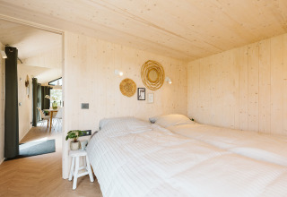 Camera da letto nella tiny house Punt al parco vacanze De Klepperstee, Paesi Bassi, con pareti in legno.