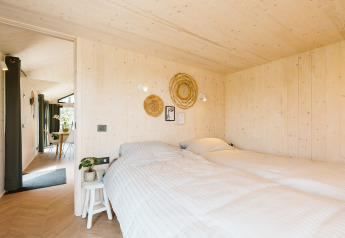 Dormitorio en Punt tiny house en el parque vacacional De Klepperstee, Países Bajos, con paredes de madera.