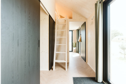 Interior of Punt tiny house at Holiday park De Klepperstee, Netherlands, showing loft and large windows.