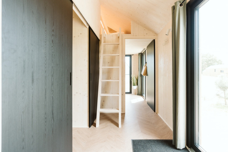 Interieur van tiny house Punt in Vakantiepark De Klepperstee, Nederland, met loft en grote ramen.