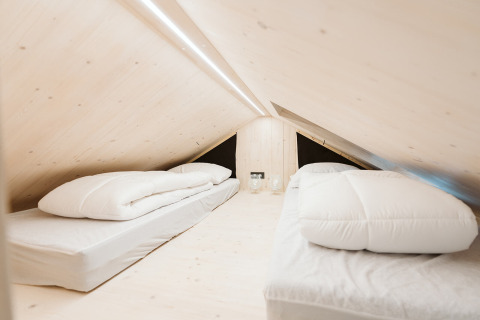 Minimalist loft bedroom with two single beds and light wood at Punt, Holiday park De Klepperstee, Netherlands.