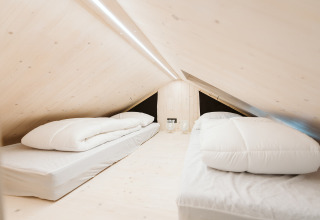 Minimalistisk loftsoveværelse med to enkeltsenge og lyse trævægge i Punt, Holiday park De Klepperstee.