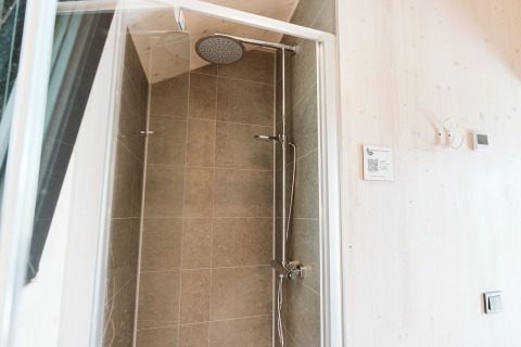 Douche de la tiny house Punt au Holiday park De Klepperstee aux Pays-Bas avec murs carrelés et pommeau pluie.