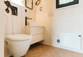 Modern badkamerinterieur in een tiny house op Holiday park De Klepperstee met zwevend toilet en houtaccenten.