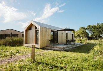 Modern wooden tiny house at Holiday park De Klepperstee, Melle, Netherlands, with deck and patio furniture