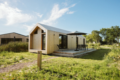 Modern wooden tiny house at Holiday park De Klepperstee, Melle, Netherlands, with deck and patio furniture
