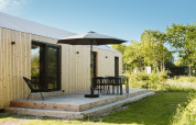 Moderne tiny house bij Holiday park De Klepperstee in Nederland met terras, parasol en buitenstoelen.