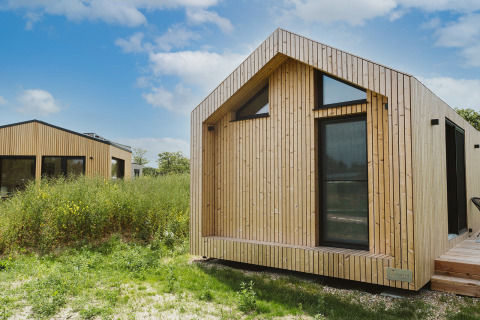 Tiny house moderne au parc De Klepperstee à Melle, Pays-Bas, entourée de verdure sous un ciel bleu.