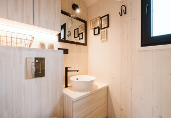 Modernes, kompaktes Badezimmer im Tiny House Melle im Ferienpark De Klepperstee, mit hellem Holz und Deko.