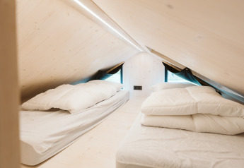 Due letti singoli sotto un soffitto inclinato nella Tiny House Melle, parco De Klepperstee, Paesi Bassi.