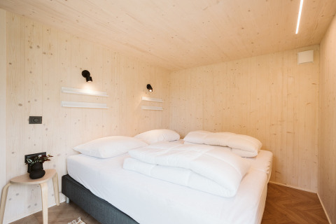 Bedroom inside the tiny house 'Melle' at Holiday park De Klepperstee, Netherlands, with light wood decor.