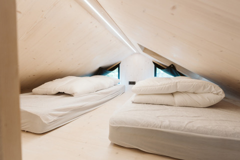 Espacio de dormitorio abuhardillado con dos camas en la tiny house Melle, De Klepperstee, Países Bajos.