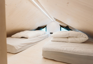 Espacio de dormitorio abuhardillado con dos camas en la tiny house Melle, De Klepperstee, Países Bajos.