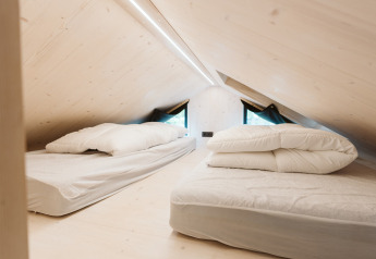 Espace nuit en mezzanine avec deux lits dans la tiny house Melle au parc De Klepperstee, Pays-Bas.