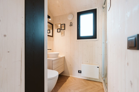 Moderne lille badeværelse med trævægge, vindue, toilet og kunstværker i Melle, De Klepperstee, Holland.
