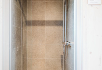 Moderne douche met glazen deur en regendouche in tiny house Melle op Holiday park De Klepperstee, Nederland.