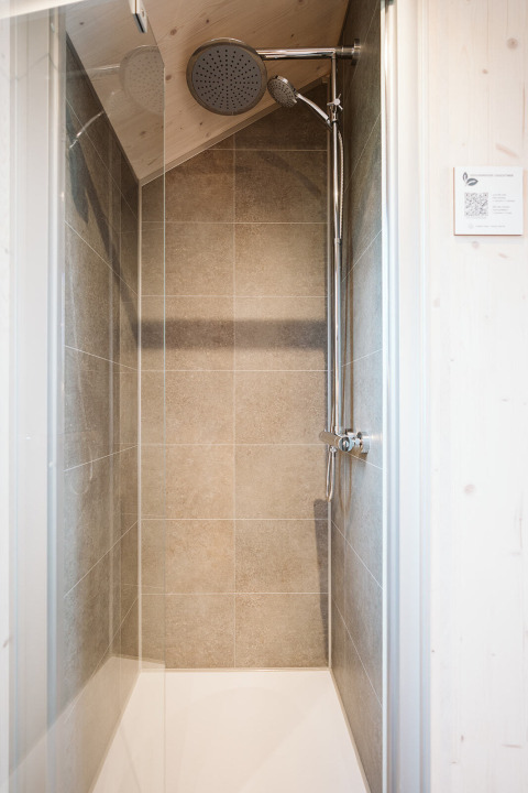 Moderne douche met glazen deur en regendouche in tiny house Melle op Holiday park De Klepperstee, Nederland.