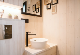Modern bathroom inside tiny house Melle with round vessel sink, black faucet, and minimalist decor.
