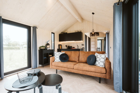 Lichte en moderne tiny house Est bij vakantiepark De Klepperstee in Nederland, met gezellige woonkamer.