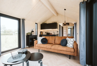 Lichte en moderne tiny house Est bij vakantiepark De Klepperstee in Nederland, met gezellige woonkamer.