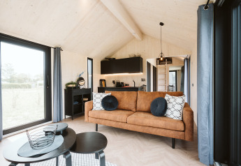 Lichte en moderne tiny house Est bij vakantiepark De Klepperstee in Nederland, met gezellige woonkamer.
