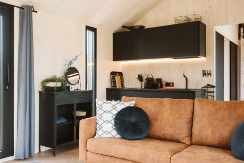Soggiorno moderno e angolo cottura nella tiny house Est al Holiday park De Klepperstee, Paesi Bassi.