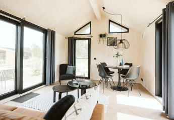 Bright, modern tiny house interior at Est in Holiday Park De Klepperstee, Netherlands, with large windows.