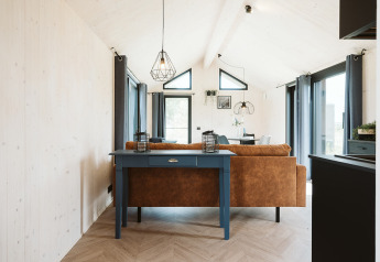 Intérieur de la tiny house Est à De Klepperstee, Pays-Bas, avec baies vitrées et décoration contemporaine.