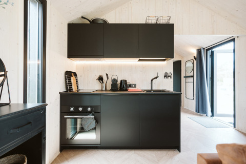 Cocina moderna y negra en la tiny house Est del Holiday park De Klepperstee en los Países Bajos, luminosa.
