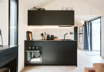 Cucina moderna nera nella tiny house Est al Holiday park De Klepperstee nei Paesi Bassi, spazio luminoso.