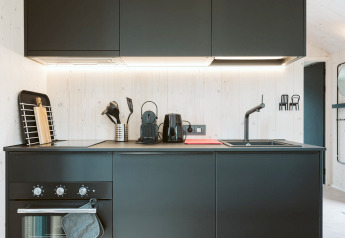 Cuisine noire moderne de la tiny house Est au Holiday Park De Klepperstee, aux Pays-Bas, au design épuré contemporain.