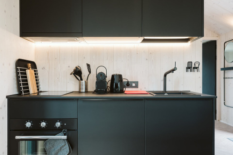 Moderne schwarze Küche im Tiny House Est im Holiday Park De Klepperstee in den Niederlanden, stilvoll eingerichtet.