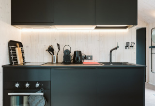 Moderne schwarze Küche im Tiny House Est im Holiday Park De Klepperstee in den Niederlanden, stilvoll eingerichtet.