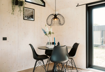 Moderner Essbereich im Tiny House Est im Ferienpark De Klepperstee, Niederlande, mit schwarzem Mobiliar.